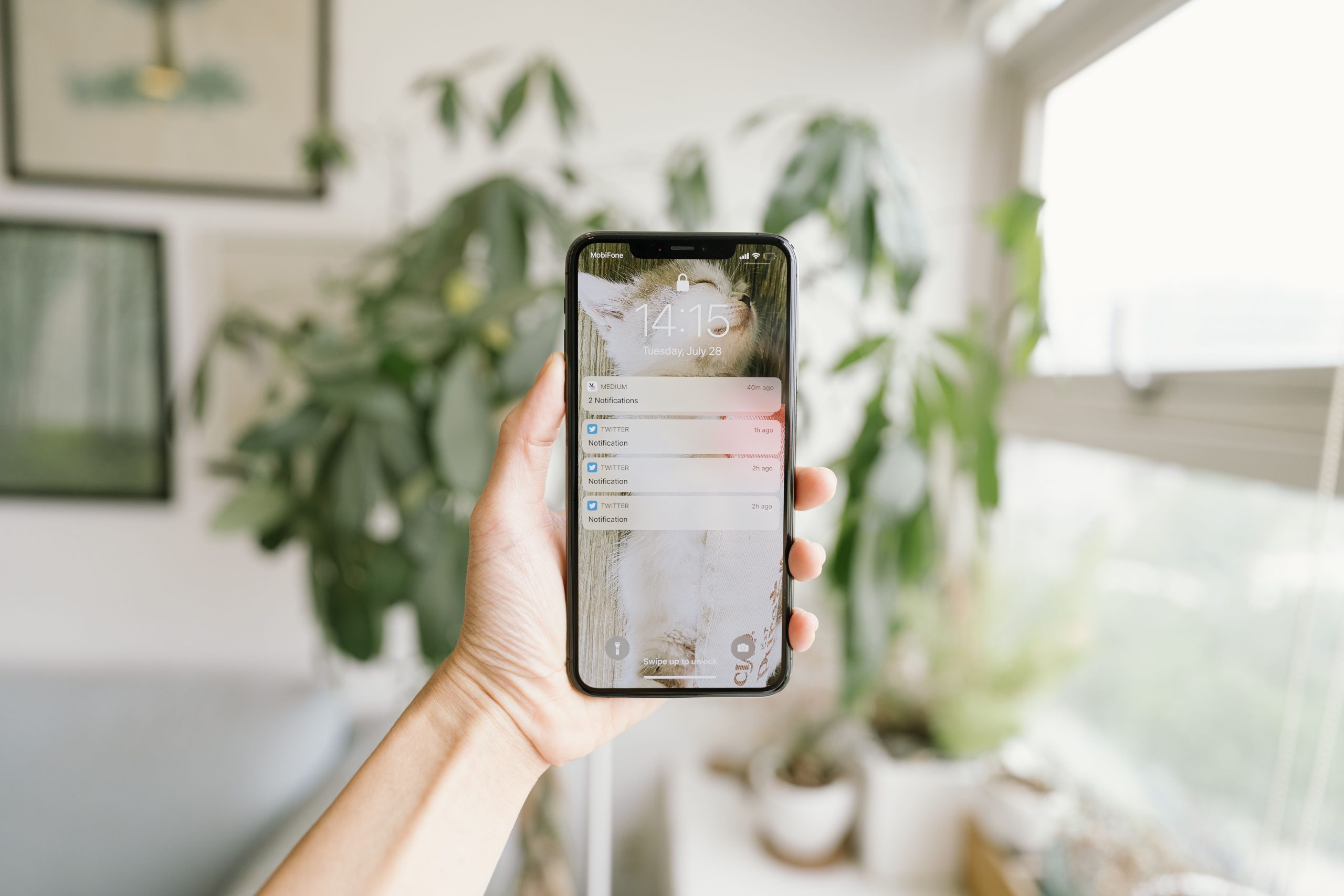 Main tenant un smartphone dans une pièce moderne lumineuse