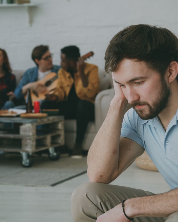Jeune homme seul et triste parmi ses amis