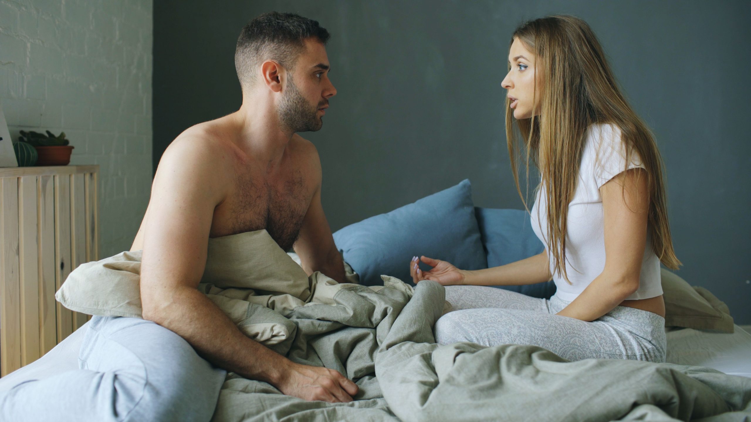 Jeune couple discutant sur le lit confortablement