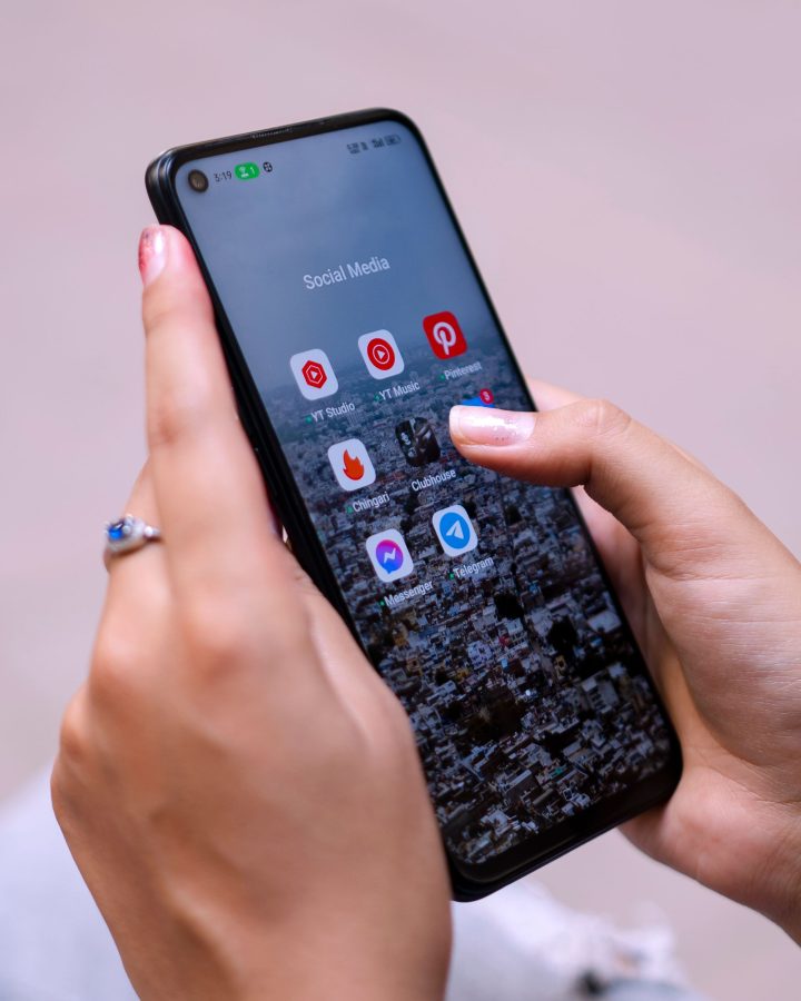 Mains tenant un smartphone affichant les réseaux sociaux