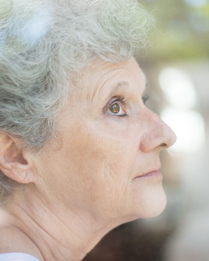 Femme âgée aux cheveux gris regardant par la fenêtre
