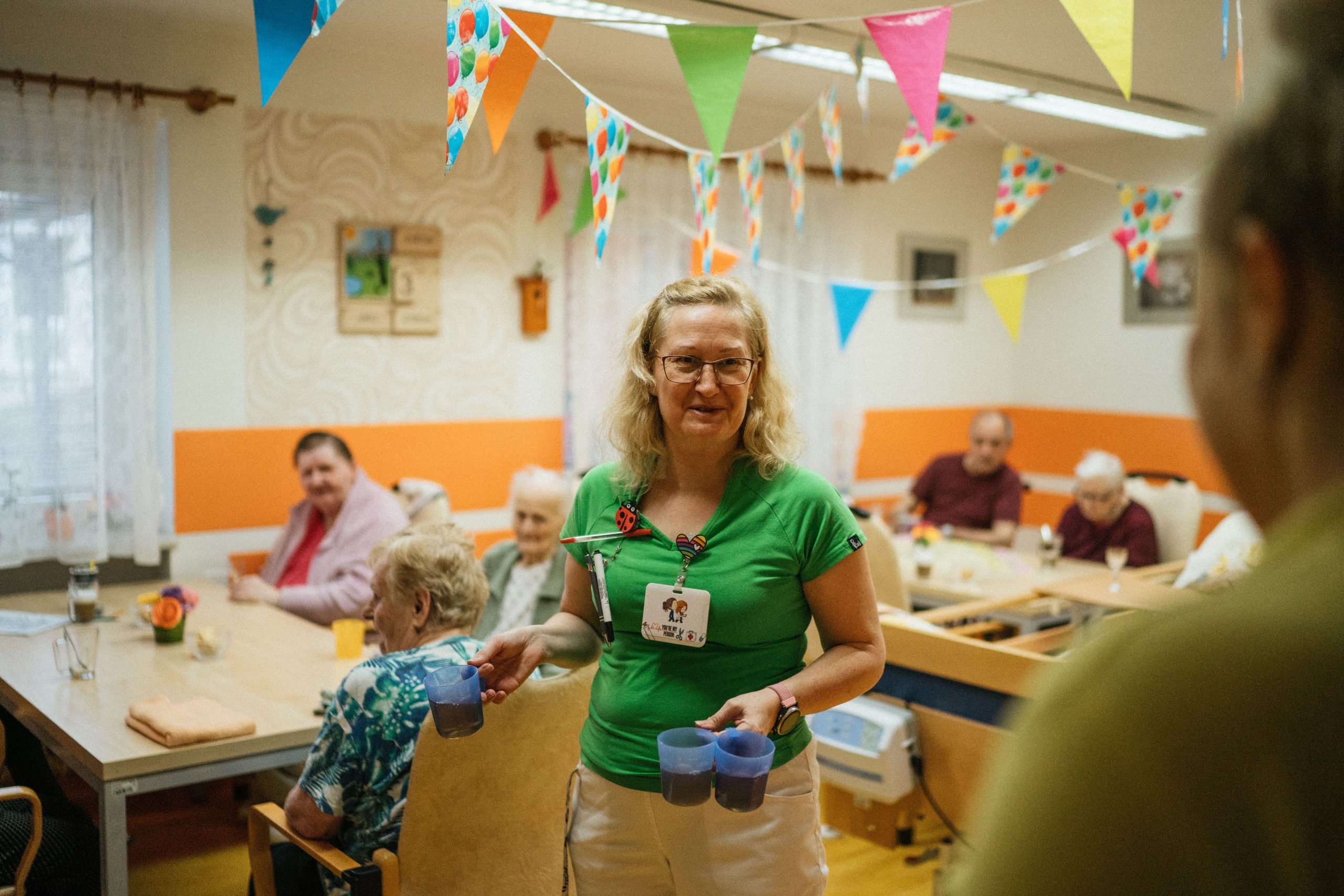 Soignante servant une boisson à des résidents souriants