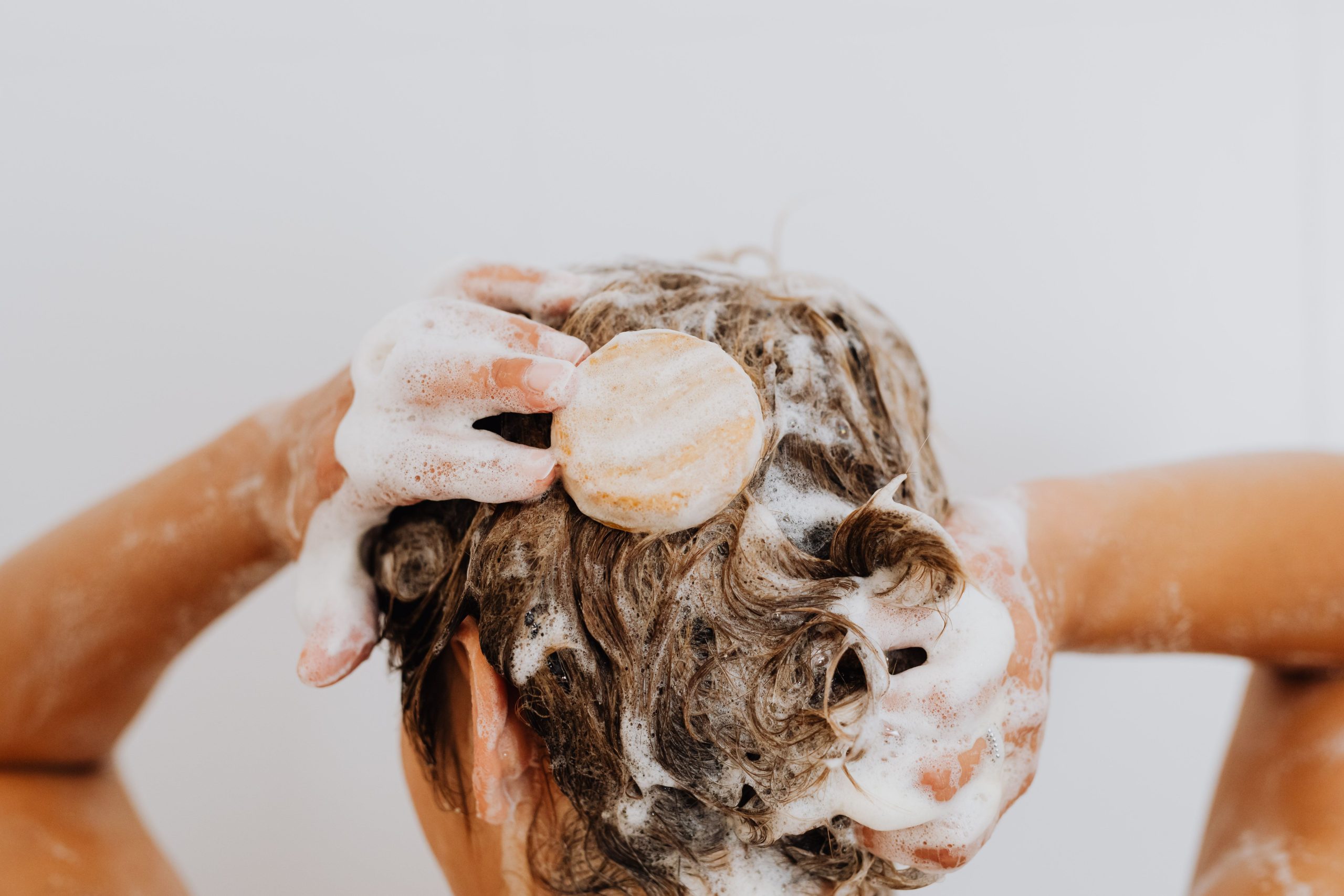 Gros plan sur les mains savonnant les cheveux